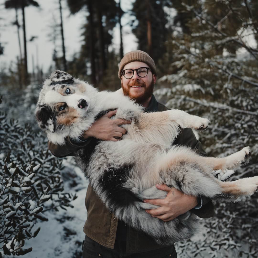 Kingston holding his Australian shepherd in a snowy forest